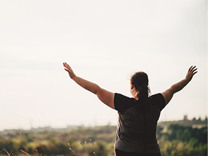 overvektig kvinne på fjelltopp.