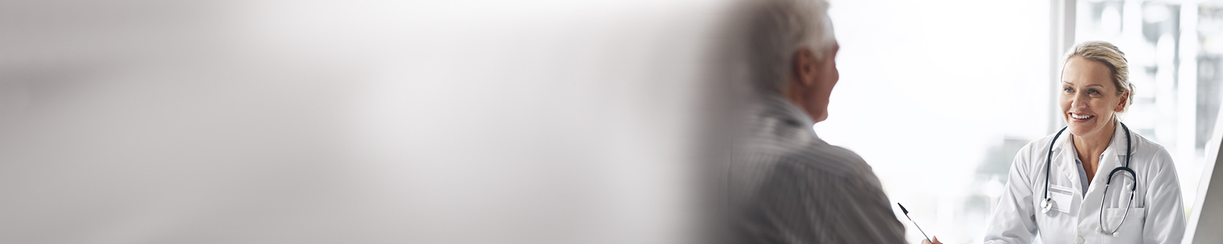 Kvinnelig allmennlege som smiler til pasient.