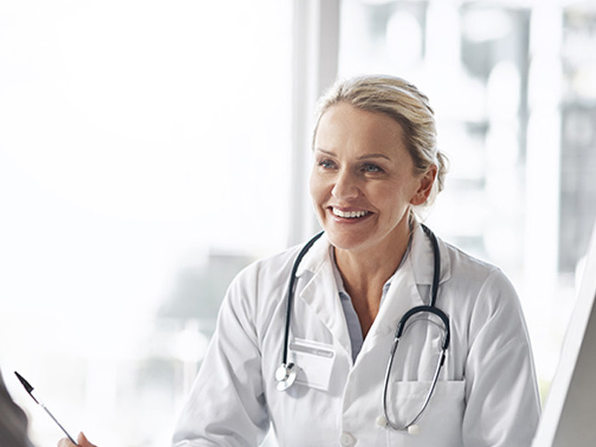 Kvinnelig allmennlege som smiler til pasient.