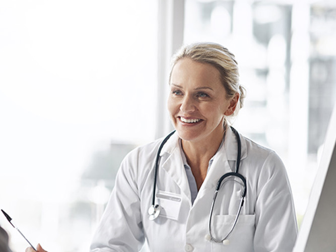 Kvinnelig allmennlege som smiler til pasient.