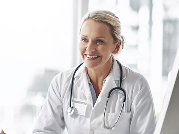 Kvinnelig allmennlege som smiler til pasient.