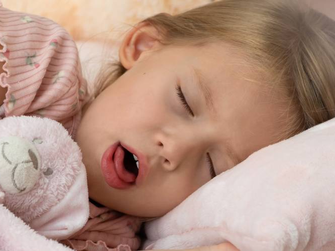 Jente som ligger i sengen og er syk