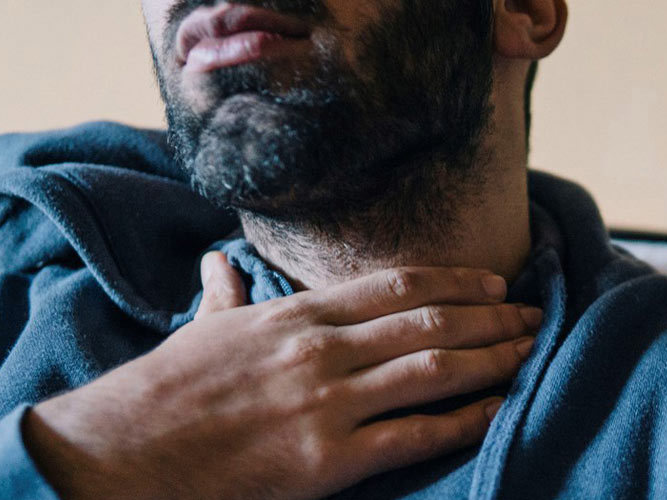 mann tar seg til halsen. foto.