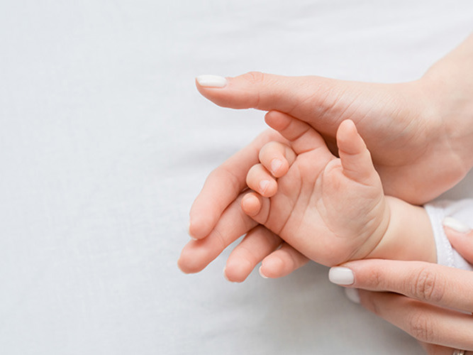 En baby hånd som ligger i moren sin hånd.