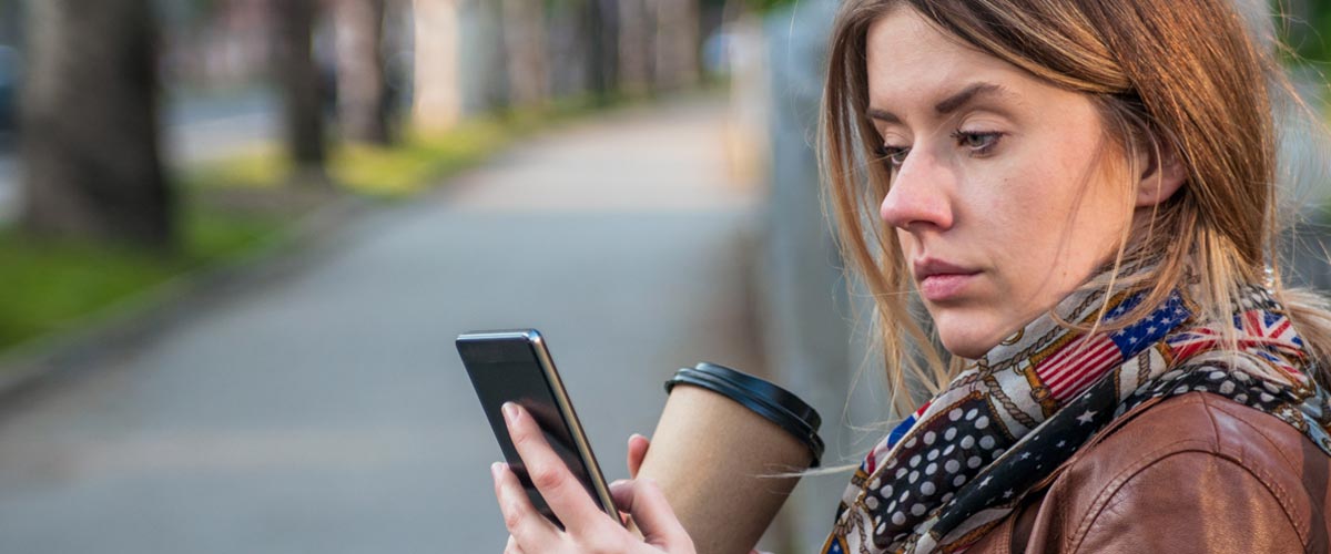 Dame i brun skinnjakke som ser på mobilen.