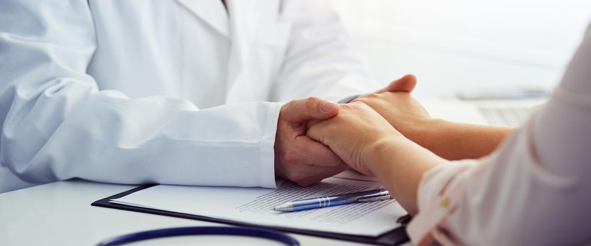 Lege som holder hendene til pasient