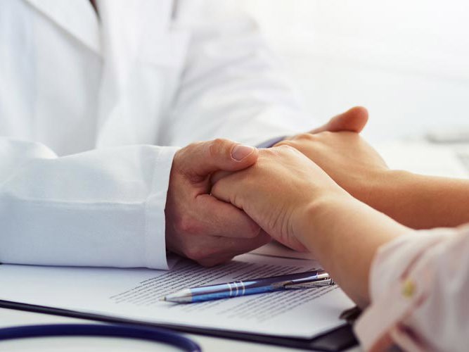 Lege som holder hendene til pasient