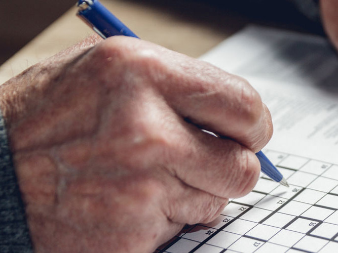 Eldre mann som løser kryssord.