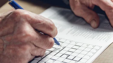 Eldre mann som løser kryssord.