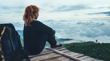 Kvinne på tur i skogen som sitter og nyter utsikten.