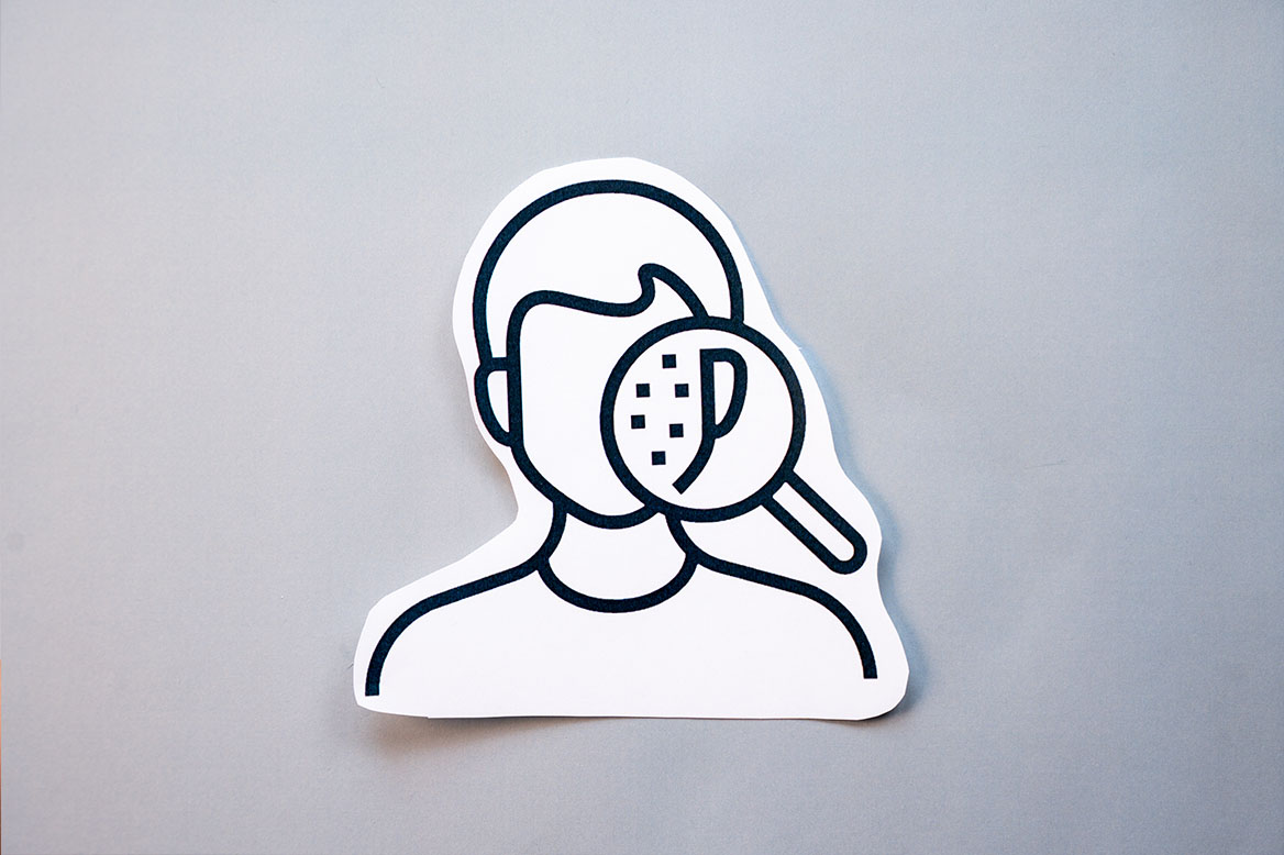 illustrasjon av et ansikt med noen prikker som sees gjennom et forstørrelsesglass. 