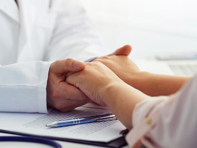 Lege som holder pasient i hendene