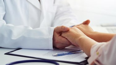 Lege som holder pasient i hendene