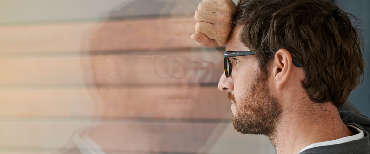 bekymret mann lener seg mot vindu. 