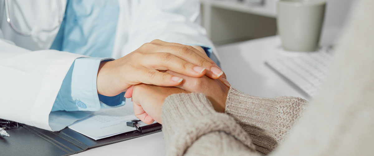 lege som holder hånden sin over hånden til en pasient. 