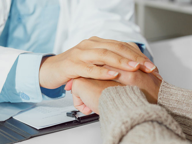 lege som holder hånden sin over hånden til en pasient.