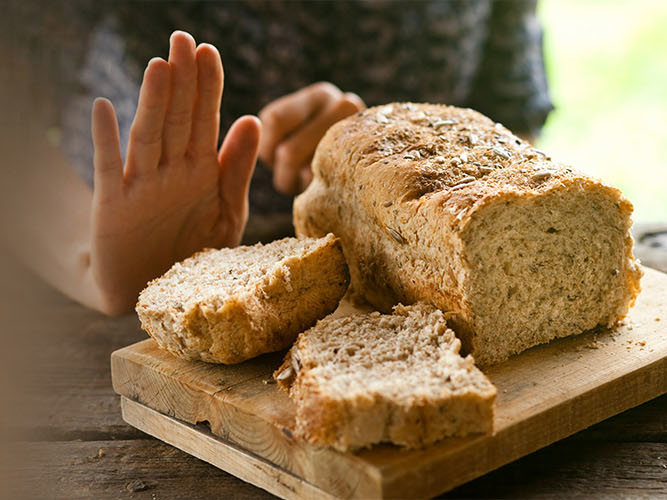En hånd som sier nei takk til brød som inneholder gluten.