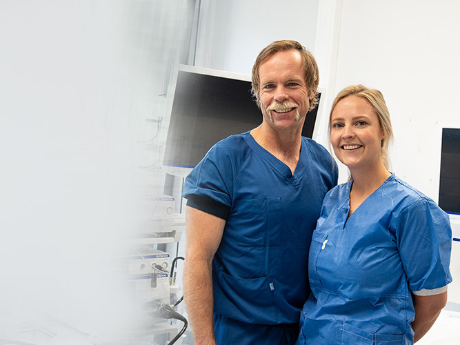 En mann og en kvinne smiler til kamera. Begge to arbeider på Aleris gastroavdeling.