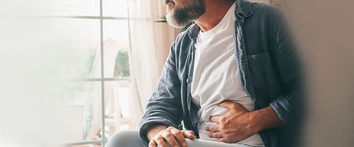 Mann som holder seg til magen grunnet magesmerter.