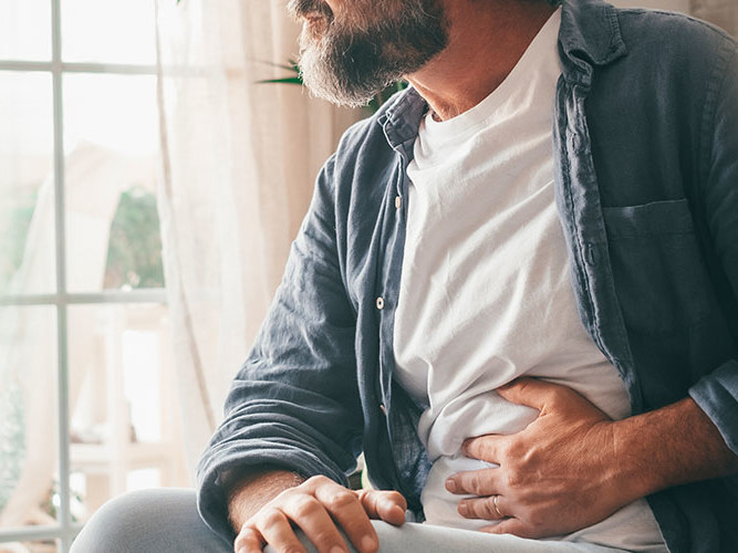 Mann som holder seg til magen grunnet magesmerter.