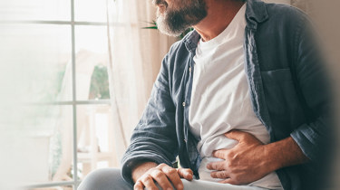 Mann som holder seg til magen grunnet magesmerter.