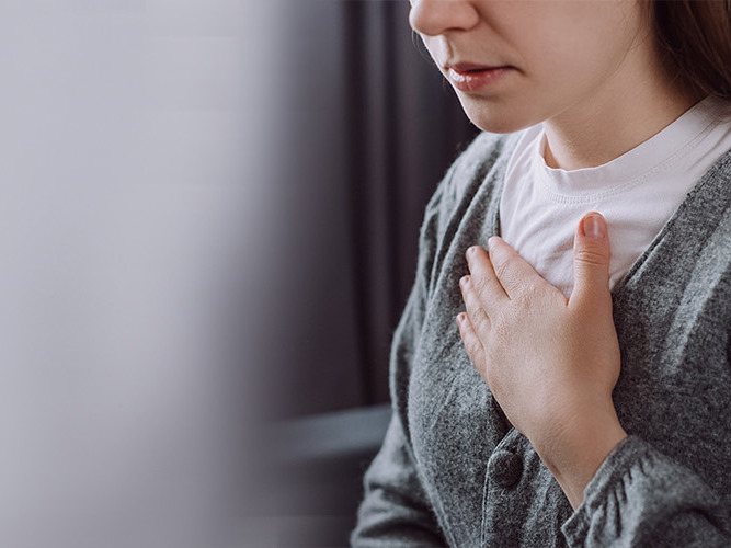 Nærbilde av kvinne som holder seg til brystet.