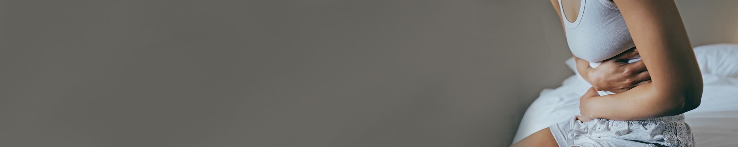 Nærbilde av en kvinne som holder seg til magen.