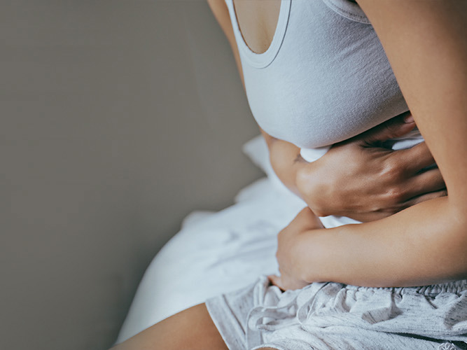 Nærbilde av en kvinne som holder seg til magen.