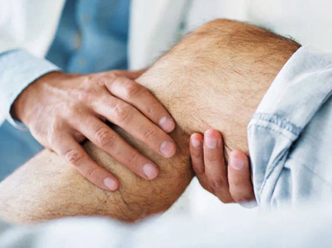 Lege holder i kneet til pasient