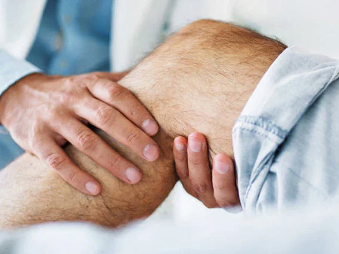 Lege holder i kneet til pasient