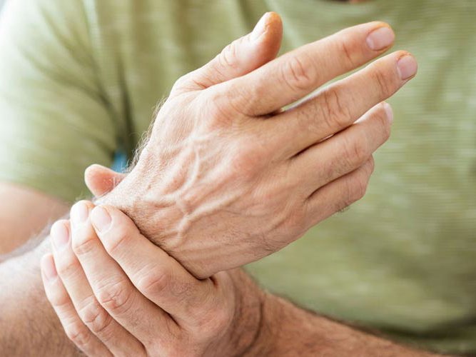 En person med grønn skjorte holder seg rundt håndleddet.