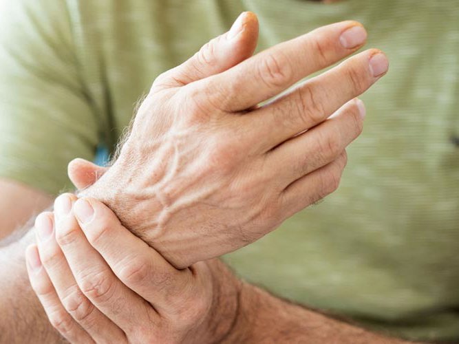 En person med grønn skjorte holder seg rundt håndleddet.