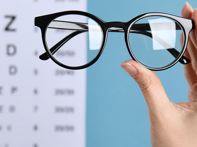 briller med synstest-kart i bakgrunnen.