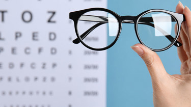 briller med synstest-kart i bakgrunnen.