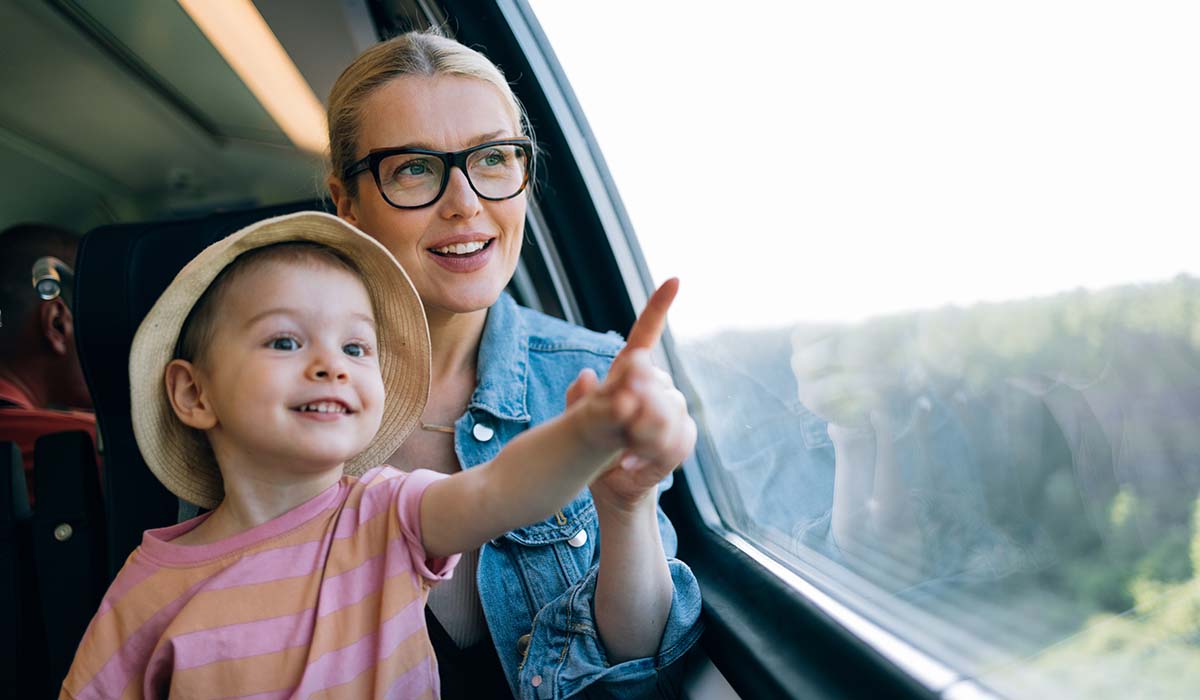 mor og datter sitter på toget og ser ut vinduet. 