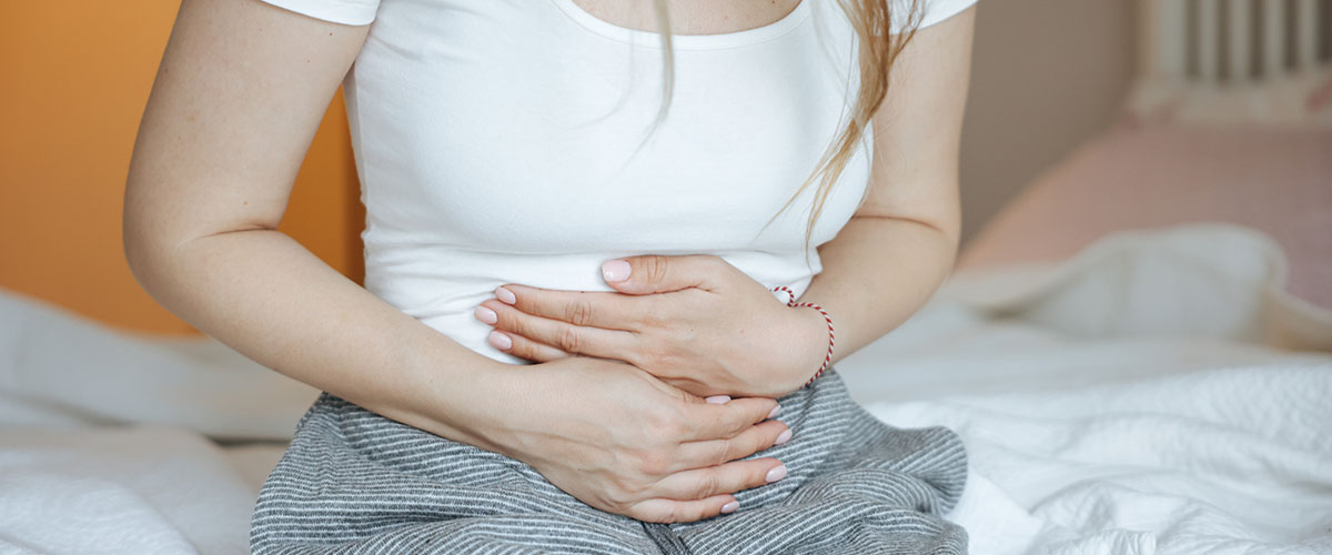 kvinne som holder seg til magen. 