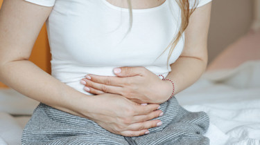 kvinne som holder seg til magen.