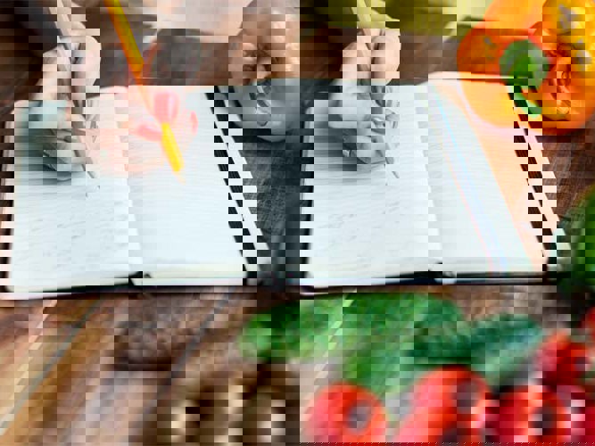 fargerik mat og en notatbok på en kjøkkenbenk.