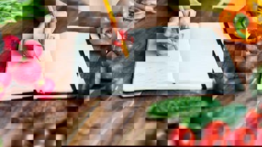 fargerik mat og en notatbok på en kjøkkenbenk.