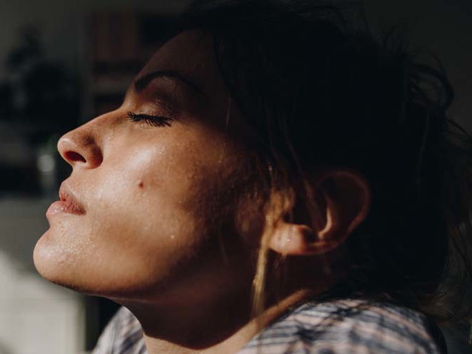 kvinne som får litt lys på ansiktet i et ellers mørkt rom.