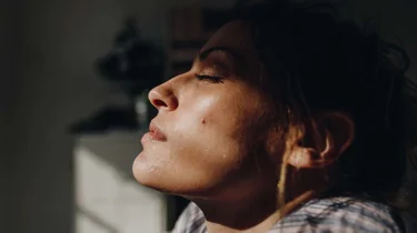 kvinne som får litt lys på ansiktet i et ellers mørkt rom.